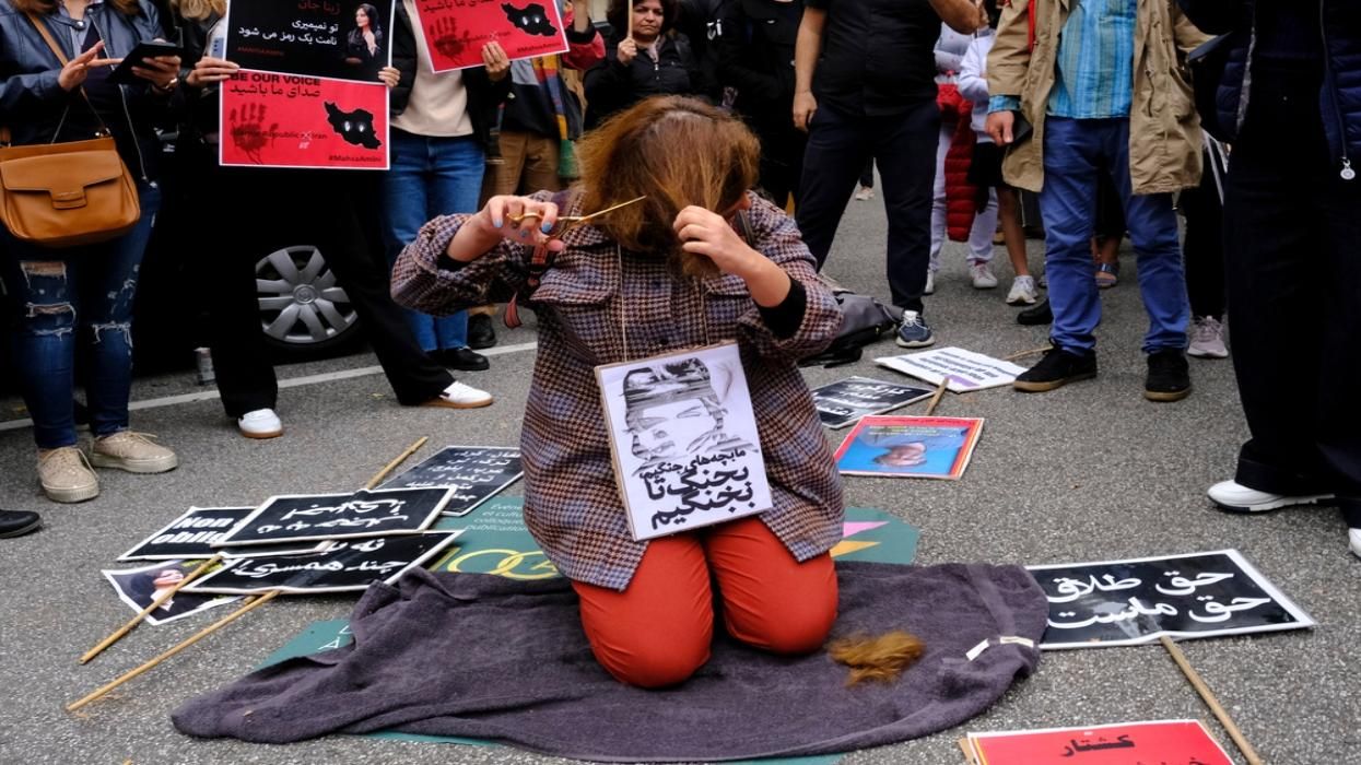 A woman cuts her hair at a protest in support of Masha Amini