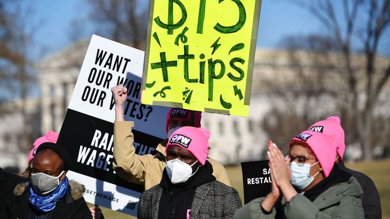 An activist holds a placard demanding a $15 an hour minimum wage and tips for restaurant workers during a rally at the US Capitol on February 8, 2022.