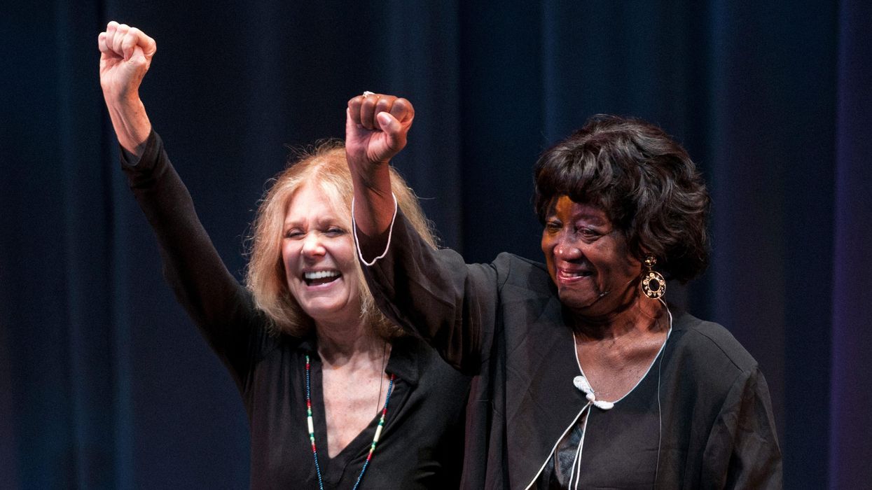 Gloria Steinem, left, and Dorothy Pitman Hughes (right) raise their fists together, resembling a photograph taken during the height of their activism together.