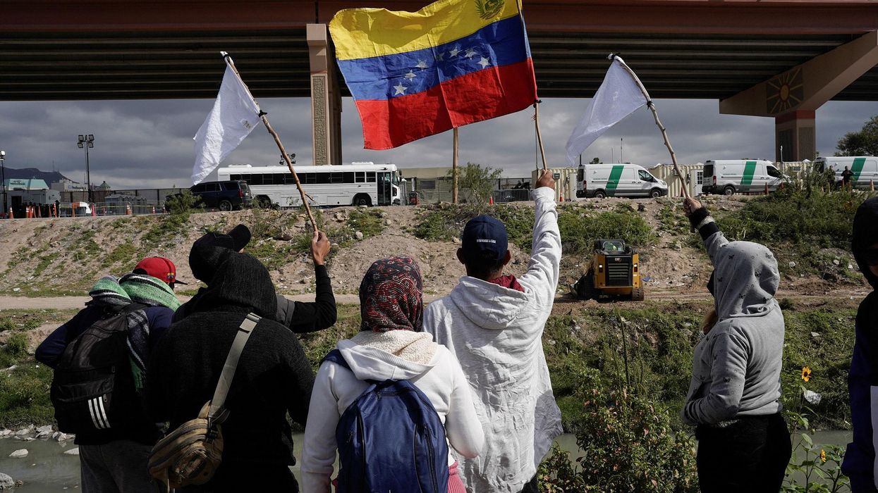 Migrants wave flags on the banks of the Rio Grande Tuesday while peacefully protesting the new US migration enforcement rules.
