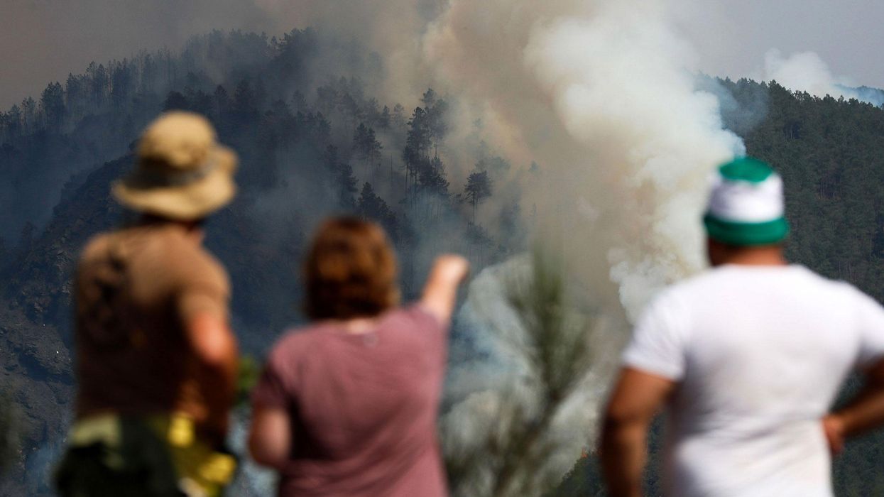 Residents watch as a column of smoke emerges from a forest fire in Galicia, Spain, on July 17.