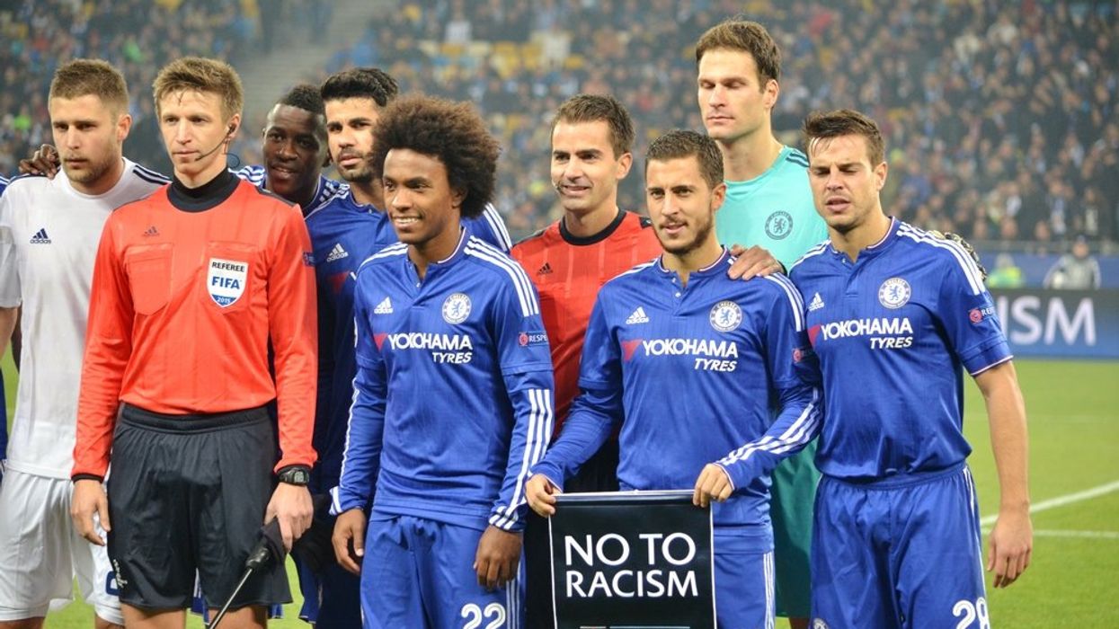 Soccer players pose with a "No to racism" sign